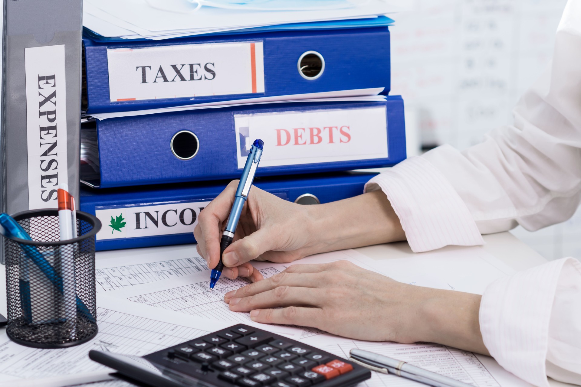 Person accounting incomes and expenses of a company, calculating taxes, concept of work in accountant department Person accounting incomes and expenses of a company, calculating taxes, concept of work in accountant department